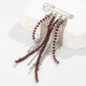 Détail d'une broche épingle argentée avec perles de cristal rouge foncé et longs glands