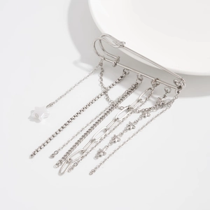 Detail of silver safety pin brooch with metallic chain tassels and star pendants