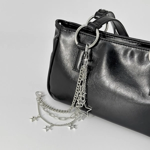 Detalle de adorno de cadena multicapa con estrellas en un bolso de cuero negro