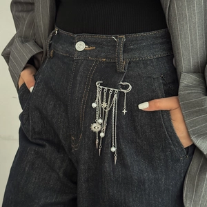 Silver safety pin brooch with devil eye sun pendant and pearl chains on denim