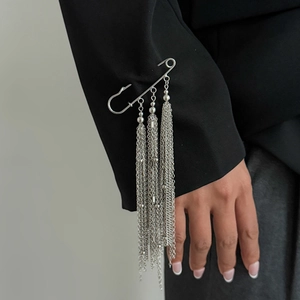 Silver metal chain brooch with star tassels on a black blazer sleeve for a trendy look