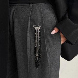 Detail of layered silver tassel safety pin brooch with black beads on a grey suit pocket