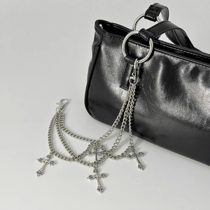 Detalle de cadena multicapa plateada para bolso con colgantes de cruz en bolso negro