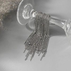 Macro shot of silver multi-layered long tassel jewelry with beads hanging on a glass
