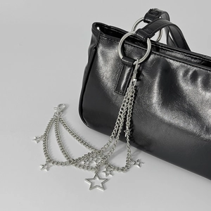 Detalle de cadena multicapa plateada con estrellas en un bolso de cuero negro