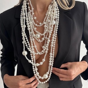 Close-up of layered baroque pearl necklace with various sizes on a black blazer model