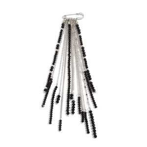 Macro shot of stylish silver safety pin brooch with black bead tassels and metal chains