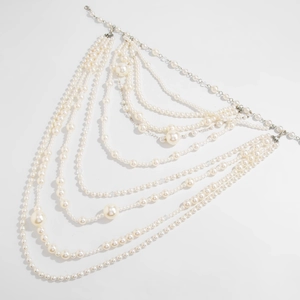 Macro detail of multilayer pearl body chain with intricate white beads and silver clasps