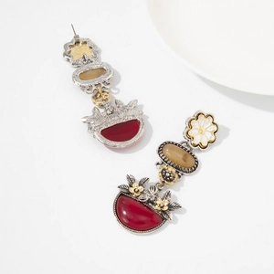Dettaglio di orecchini vintage con gemme rosse, fiori bianchi e finitura in argento