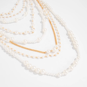 Close-up of layered baroque pearl necklace with golden metal chains and intricate textures