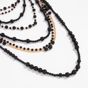 Close-up of layered baroque black pearls and gold alloy chains with vintage texture