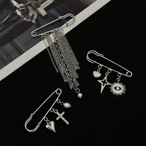 Dettaglio di spille da balia in argento con ciondoli a stella, cuore e nappe eleganti