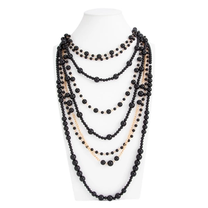 Detail of layered long necklace featuring black glossy beads and golden chains on model