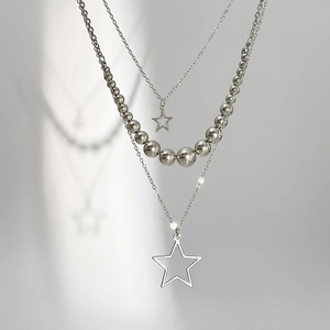 Detail of silver triple-layered necklace with star pendants and polished bead chain