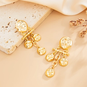 Dettaglio di orecchini vintage in oro martellato con accenti floreali su seta beige