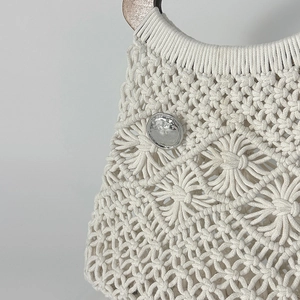 Dettaglio della borsa in macramè bianco con trama floreale e fibbia in metallo argento