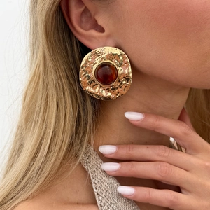 Close-up of vintage gold hammer-textured round earrings with amber resin gemstones