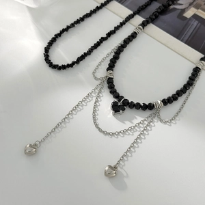 Vue macro détaillée des perles de cristal noires et des pendentifs cœur sur le collier