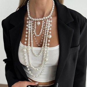 Detail van gelaagde witte imitatieparelketting met zilveren details en retro drapering