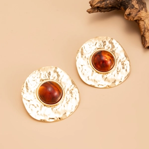 Close-up of vintage hammered gold earrings with large amber resin center stones