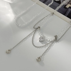 Détail de pendentifs cœurs argentés superposés avec perles de cristal brillantes