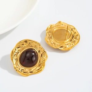 Detailed close-up of vintage gold stud earrings with dark red oval gemstones on white background