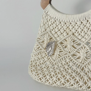 Dettaglio di borsa macramè fatta a mano con spilla a foglia argento e manici in legno