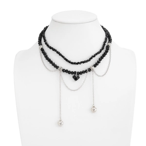 Détail d'un collier double couche avec perles noires et pendentifs en forme de cœur
