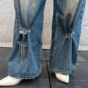 Épingles de sûreté en argent avec charms croix cœur et pompons sur un jean