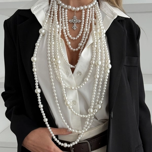 Detail van een gelaagde barokke parelketting met een vintage strass kruis hanger
