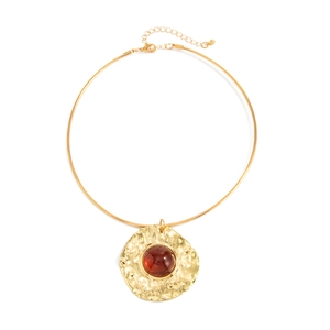 Gold choker necklace with hammered round pendant and red-brown gemstone inlay