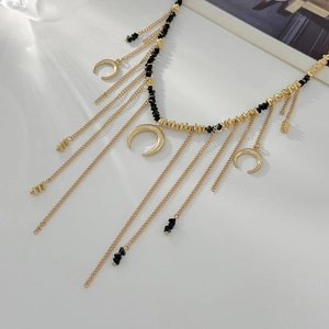 Détail d'un collier doré multicouche avec pendentifs demi-lune et perles noires facettées