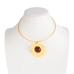Detailed macro view of hammered gold choker with large inset amber gemstone on white mannequin