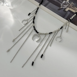 Détail de pendentifs lune argentés et perles noires sur collier à franges multicouche