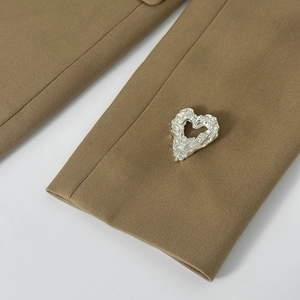 Dettaglio macro della spilla a cuore d'argento con texture lavica su tessuto kaki
