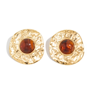 Detailed view of large vintage gold earrings with hammered texture and amber resin stone