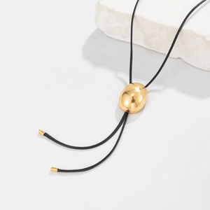 Detalle del deslizador ovalado dorado y el cordón de cuero negro de un collar ajustable