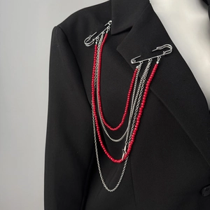 Détail d'une broche punk avec chaînes de perles rouges et étoile sur un revers noir