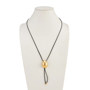 Detalle de un colgante ovalado dorado pulido en un collar de cordón negro minimalista