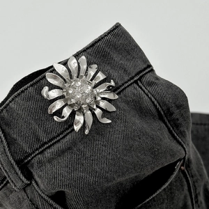 Macro di una spilla a cigno argento con cristalli scintillanti su tessuto denim nero