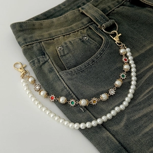 Detail of double-layer pearl belt chain with colorful crystals on denim jeans