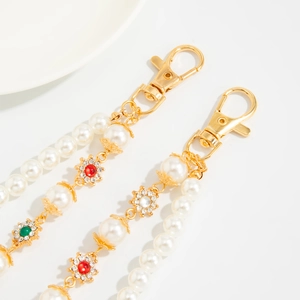 Detail of faux pearl bag charm with gold lobster clasp and rhinestone floral accents