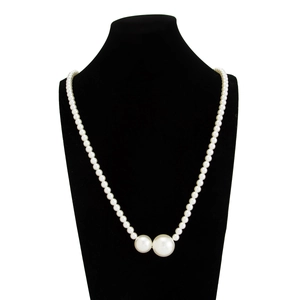 Detail van witte parelketting met twee extra grote accentparels op een zwart bustestandaard