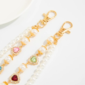 Detail of faux pearl bag charm with colorful rhinestone heart charms and gold clasp