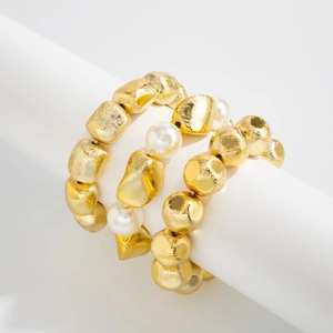 Detailed close-up of beaded bracelet featuring gold hammered beads and white round pearls