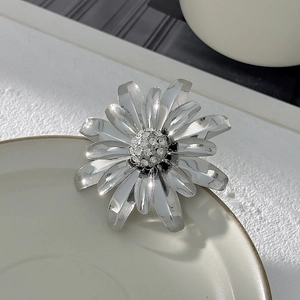 Dettaglio di una spilla a forma di margherita argento con strass e petali metallici