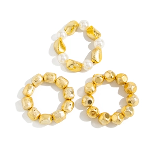 Detail of matte gold textured beads and faux pearl elastic bracelets in a 3-piece set