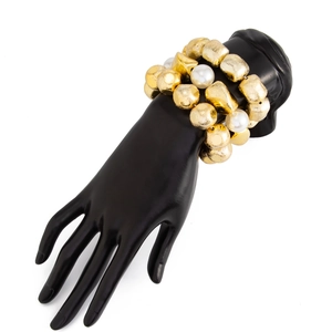 Detail of layered gold beaded bracelets with textured geometric beads and white pearls