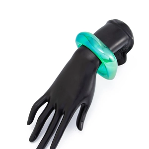 Detail eines klobigen mintgrünen Harzarmreifs auf einem schwarzen Handmodell