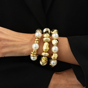 Detail of three-piece stackable bracelet set with white pearls and textured gold beads